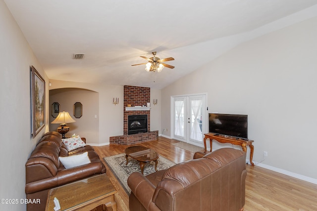 living room with vaulted ceiling, ceiling fan, a fireplace, and light hardwood / wood-style flooring