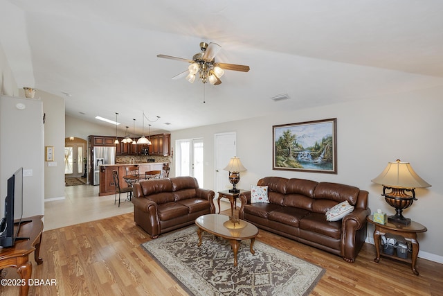 living room with ceiling fan, lofted ceiling, and light hardwood / wood-style flooring