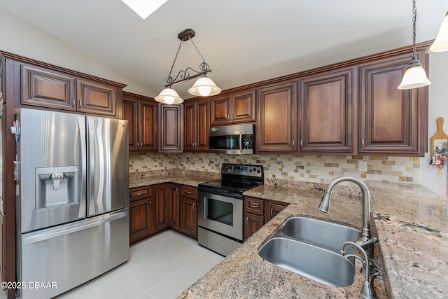 kitchen with pendant lighting, sink, appliances with stainless steel finishes, light stone counters, and decorative backsplash