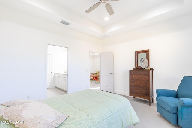 tiled bedroom with ceiling fan, connected bathroom, and a tray ceiling