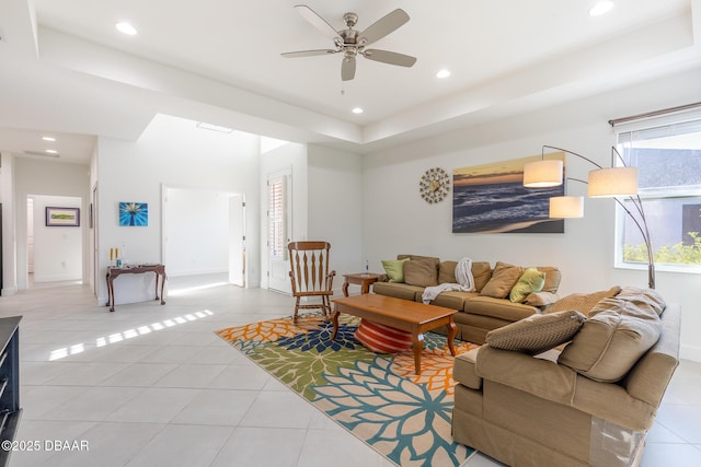 living room with light tile patterned floors, a raised ceiling, a wealth of natural light, and ceiling fan