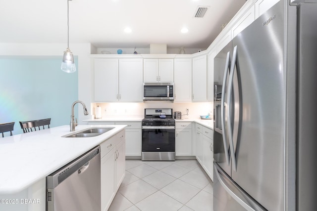 kitchen with pendant lighting, sink, appliances with stainless steel finishes, white cabinetry, and a breakfast bar area