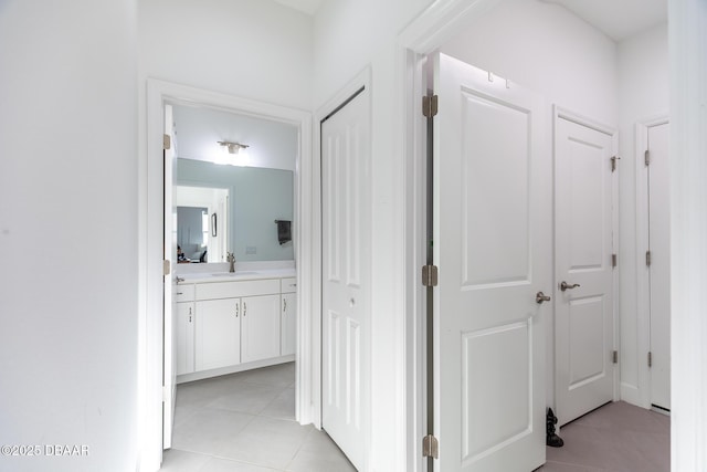 corridor featuring sink and light tile patterned flooring