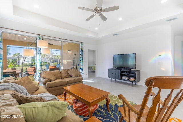 tiled living room with a raised ceiling and ceiling fan