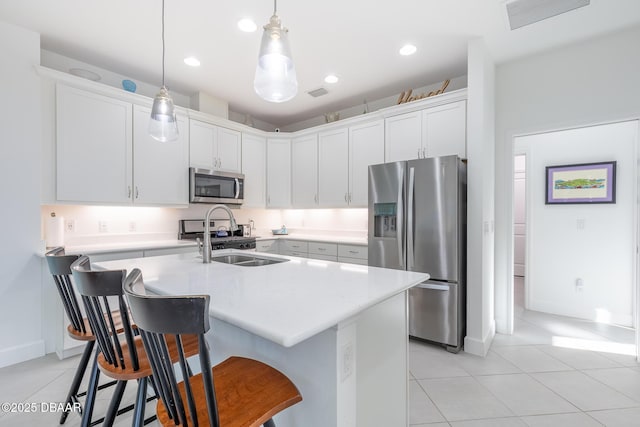 kitchen with sink, stainless steel appliances, pendant lighting, a breakfast bar area, and white cabinets