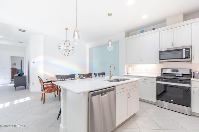 kitchen featuring a center island with sink, hanging light fixtures, sink, appliances with stainless steel finishes, and white cabinetry