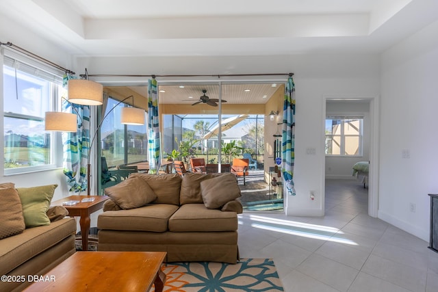 tiled living room featuring a raised ceiling, plenty of natural light, and ceiling fan