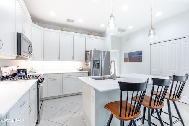 kitchen featuring appliances with stainless steel finishes, sink, pendant lighting, white cabinetry, and an island with sink