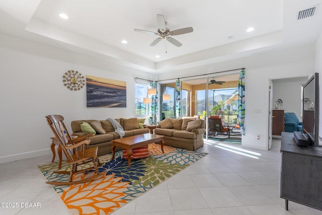 living room with ceiling fan, light tile patterned flooring, and a tray ceiling