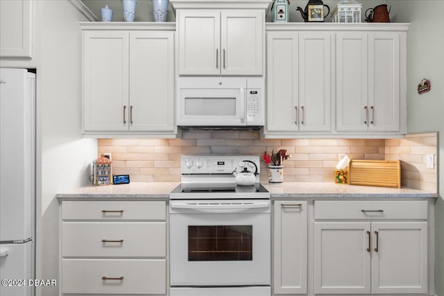 kitchen with white appliances, decorative backsplash, light stone counters, and white cabinets