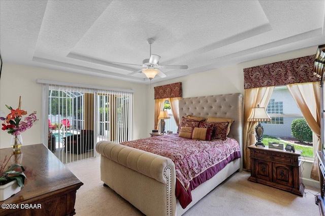 carpeted bedroom with ceiling fan, a textured ceiling, a raised ceiling, and access to outside