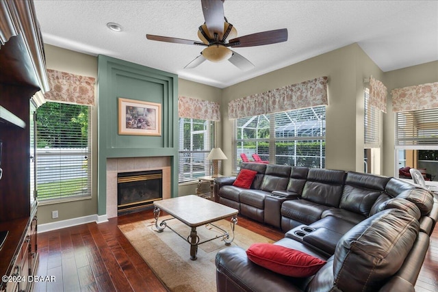 living room with dark hardwood / wood-style flooring, a textured ceiling, a tile fireplace, and a healthy amount of sunlight