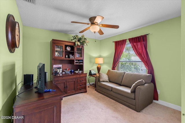 carpeted home office featuring a textured ceiling and ceiling fan