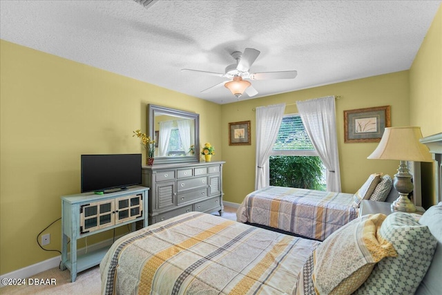 bedroom featuring a textured ceiling, light colored carpet, and ceiling fan