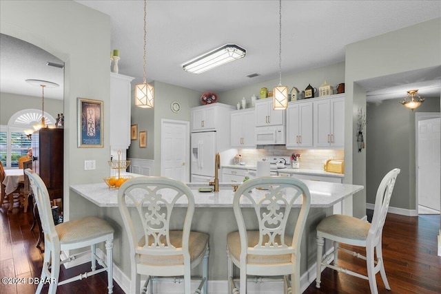 kitchen with dark wood-type flooring, white appliances, white cabinetry, and decorative light fixtures