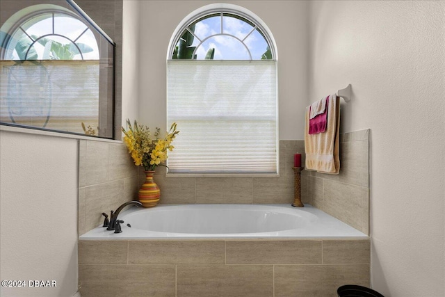 bathroom featuring plenty of natural light and a relaxing tiled tub