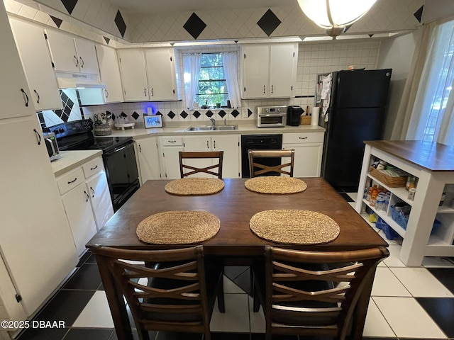 kitchen with sink, light tile patterned floors, extractor fan, white cabinets, and black appliances