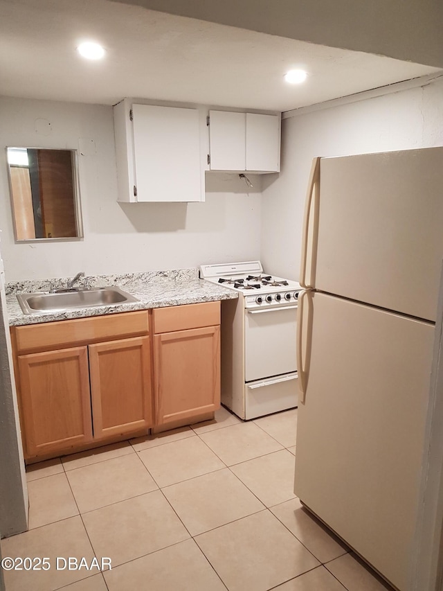 kitchen with light tile patterned flooring, sink, white cabinets, and white appliances