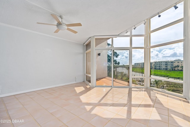 unfurnished room with baseboards, tile patterned floors, a wall of windows, a textured ceiling, and track lighting