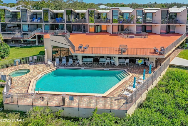 community pool with a community hot tub, a residential view, a patio, and fence