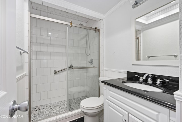 bathroom with toilet, a wainscoted wall, vanity, a stall shower, and crown molding