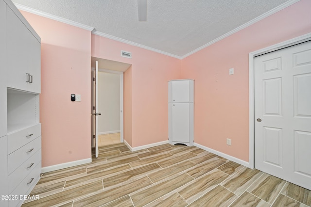 empty room featuring crown molding, a textured ceiling, visible vents, and wood tiled floor