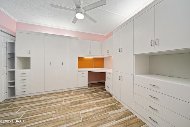 interior space with ceiling fan, light countertops, a textured ceiling, wood finish floors, and built in desk