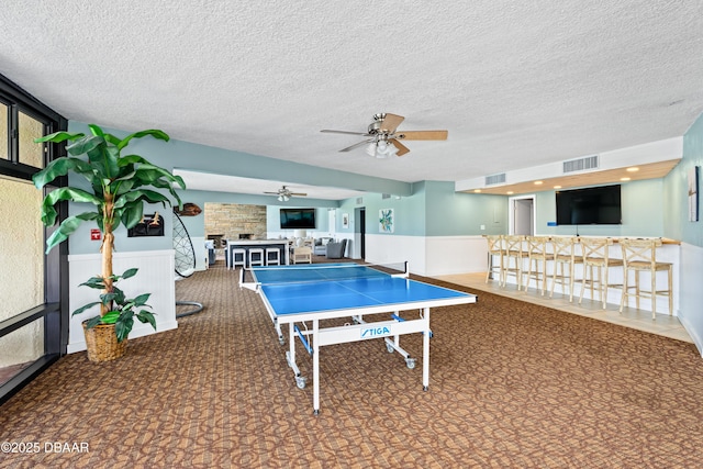 recreation room featuring a fireplace, visible vents, and wainscoting