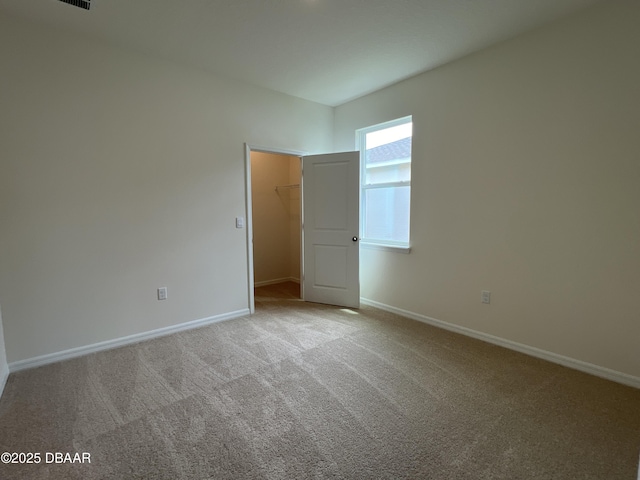 unfurnished bedroom with light carpet, a walk in closet, and a closet