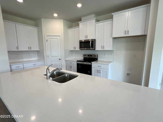 kitchen with decorative backsplash, sink, white cabinets, and appliances with stainless steel finishes