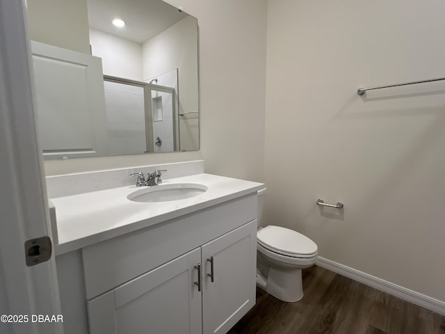 bathroom featuring vanity, hardwood / wood-style flooring, toilet, and a shower with door