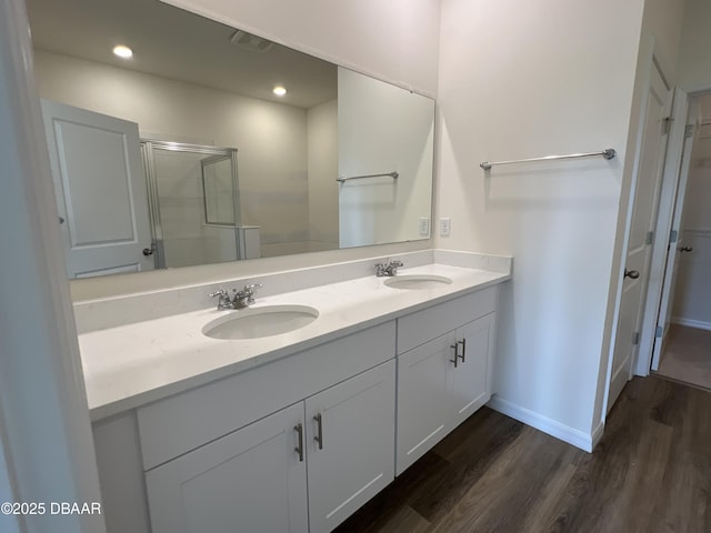 bathroom with hardwood / wood-style floors, vanity, and an enclosed shower