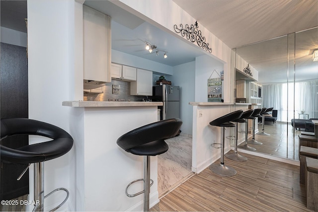 2800 N Atlantic Ave Unit 1105, Daytona Beach, FL 32118 - kitchen with a breakfast bar area, a peninsula, backsplash, light wood finished floors, and light countertops