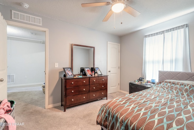 bedroom featuring a textured ceiling, light carpet, and ceiling fan