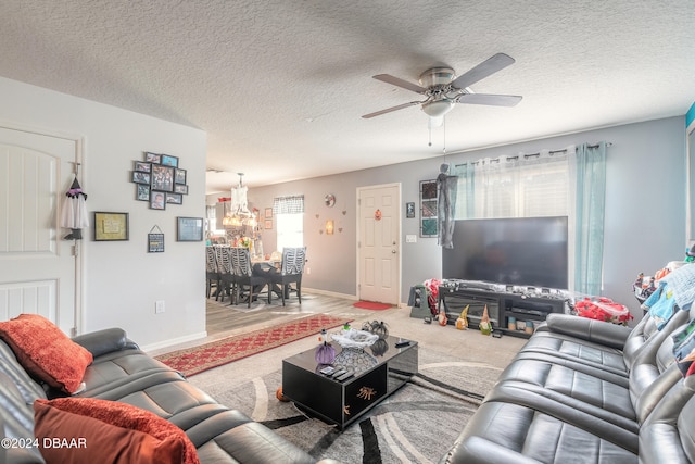 carpeted living room with a textured ceiling and ceiling fan with notable chandelier