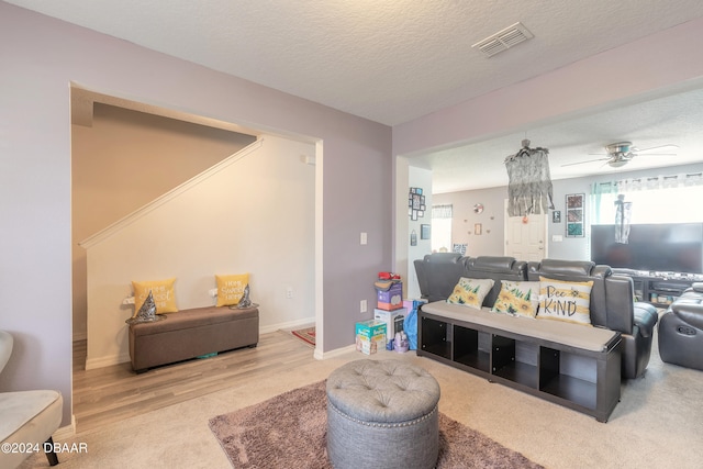 living room featuring ceiling fan, wood-type flooring, and a textured ceiling