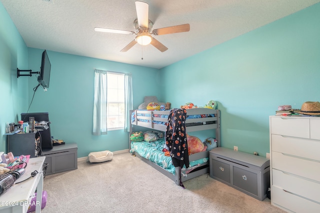 carpeted bedroom featuring ceiling fan and a textured ceiling