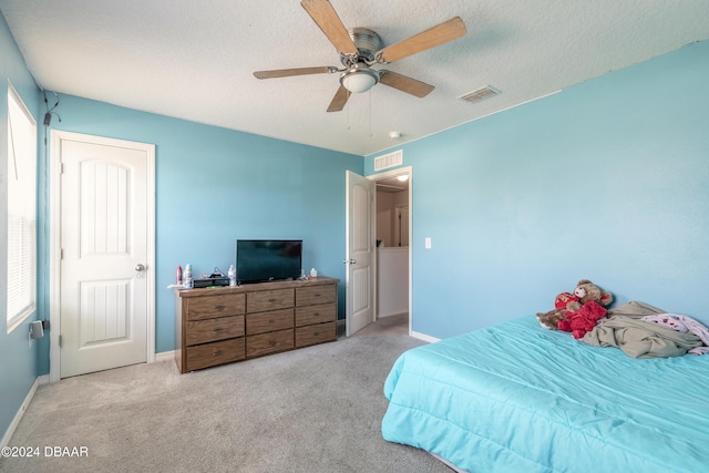 bedroom featuring a textured ceiling, light carpet, and ceiling fan