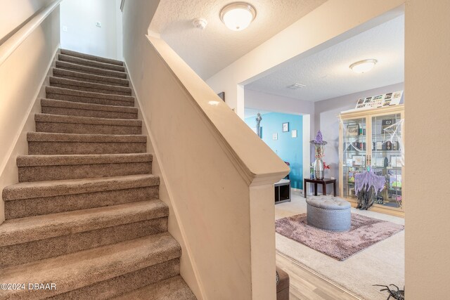 stairs with hardwood / wood-style floors and a textured ceiling