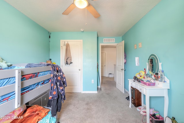 carpeted bedroom with ceiling fan and a textured ceiling