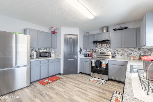 kitchen featuring range hood, appliances with stainless steel finishes, light hardwood / wood-style floors, and tasteful backsplash