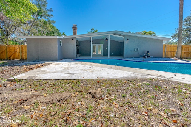 back of house featuring a fenced in pool, french doors, and a patio area