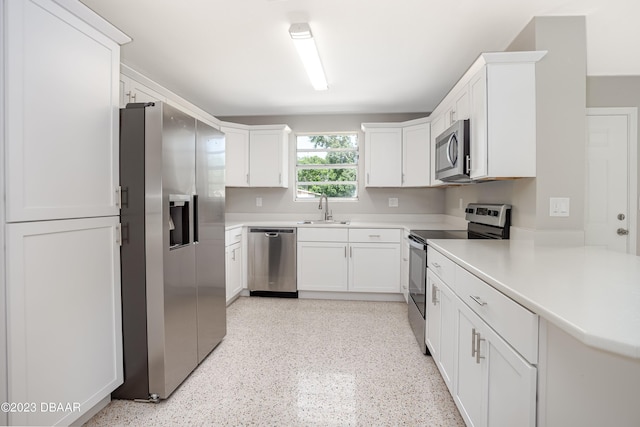 kitchen with stainless steel appliances, white cabinets, sink, and kitchen peninsula