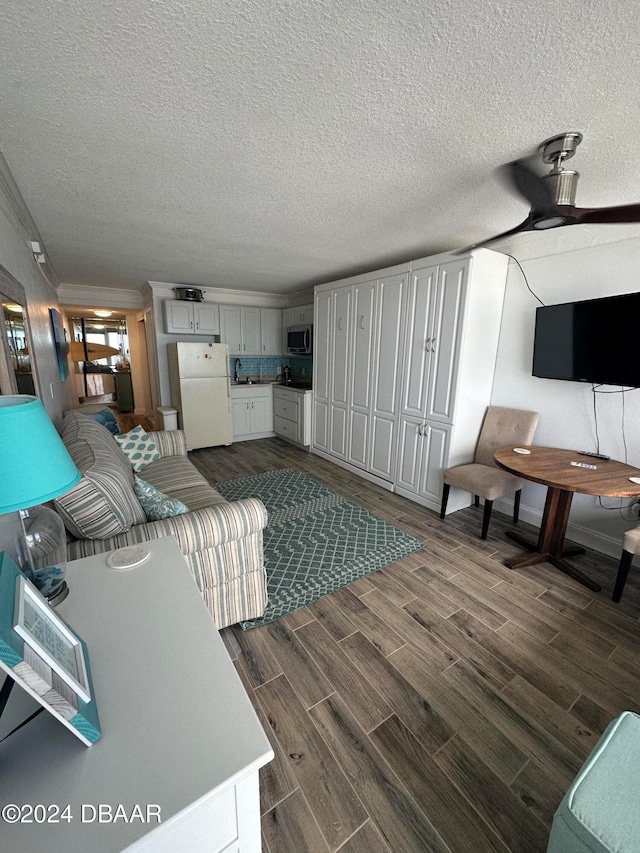 living room featuring dark wood-type flooring, a textured ceiling, and ceiling fan