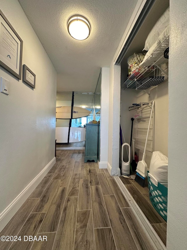 hallway with hardwood / wood-style floors and a textured ceiling