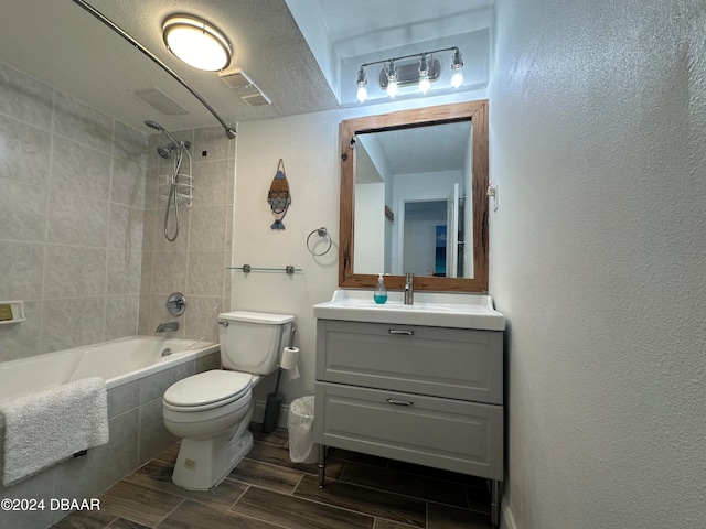 full bathroom featuring vanity, toilet, a textured ceiling, and tiled shower / bath combo