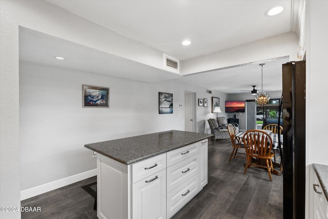 kitchen with dark wood-type flooring, black refrigerator, ceiling fan, dark stone countertops, and white cabinetry