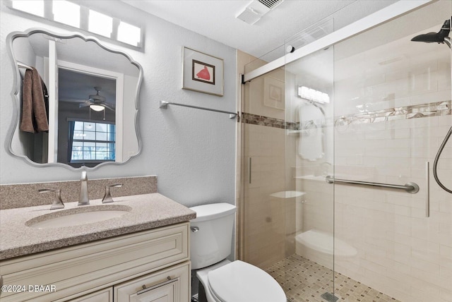 bathroom with vanity, toilet, a shower with door, and ceiling fan