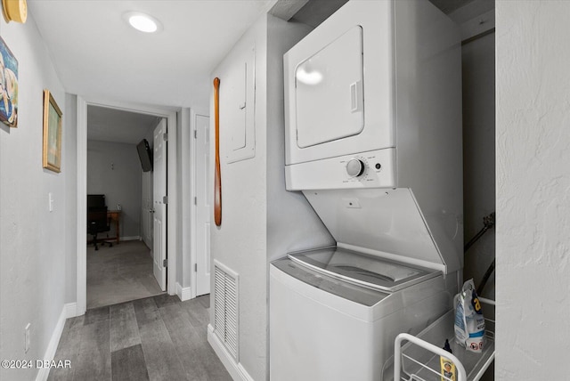 laundry area with stacked washer / drying machine and dark wood-type flooring