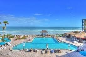 view of swimming pool with a beach view and a water view